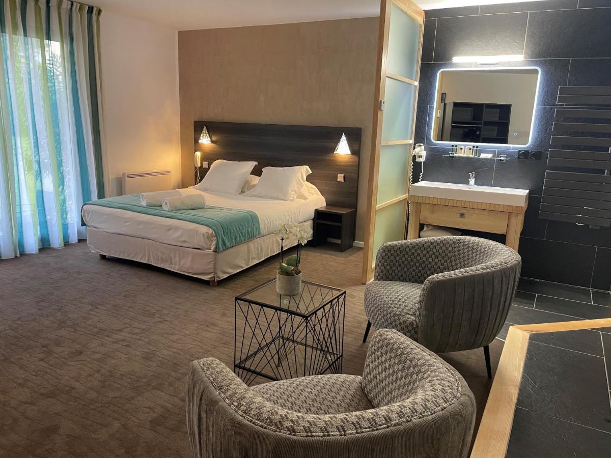 une chambre d'hôtel avec un lit et deux chaises dans l'établissement Logis Hotel Restaurant SPA Les Oliviers, à Loriol-sur-Drôme 100 autres photos