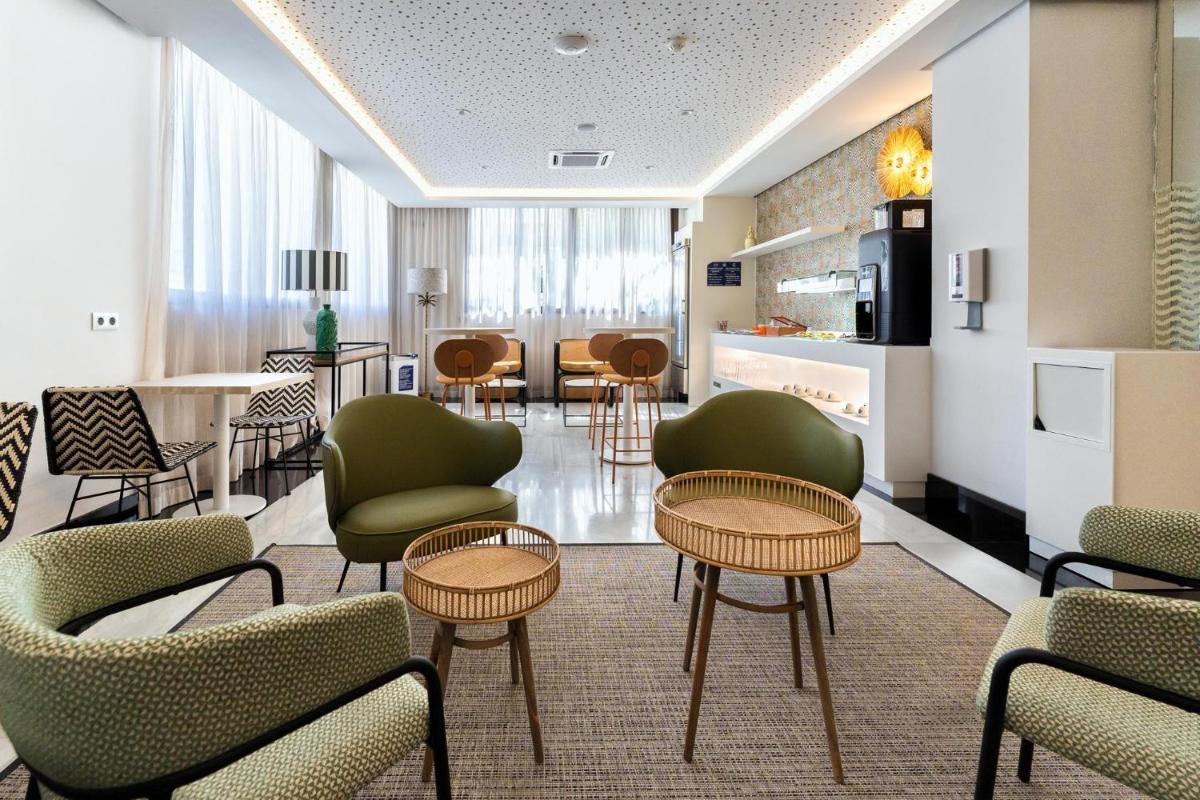 Un vestíbulo con sillas y mesas y una cocina. en Spring Hotel Bitácora, en Playa de las Américas