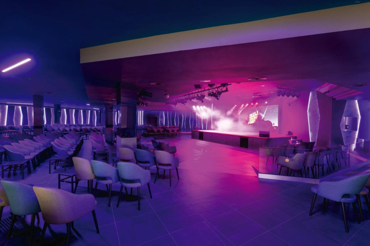 una habitación con sillas y un escenario con luces moradas en Hotel Riu Paraiso Lanzarote - All Inclusive, en Puerto del Carmen 65 fotos más