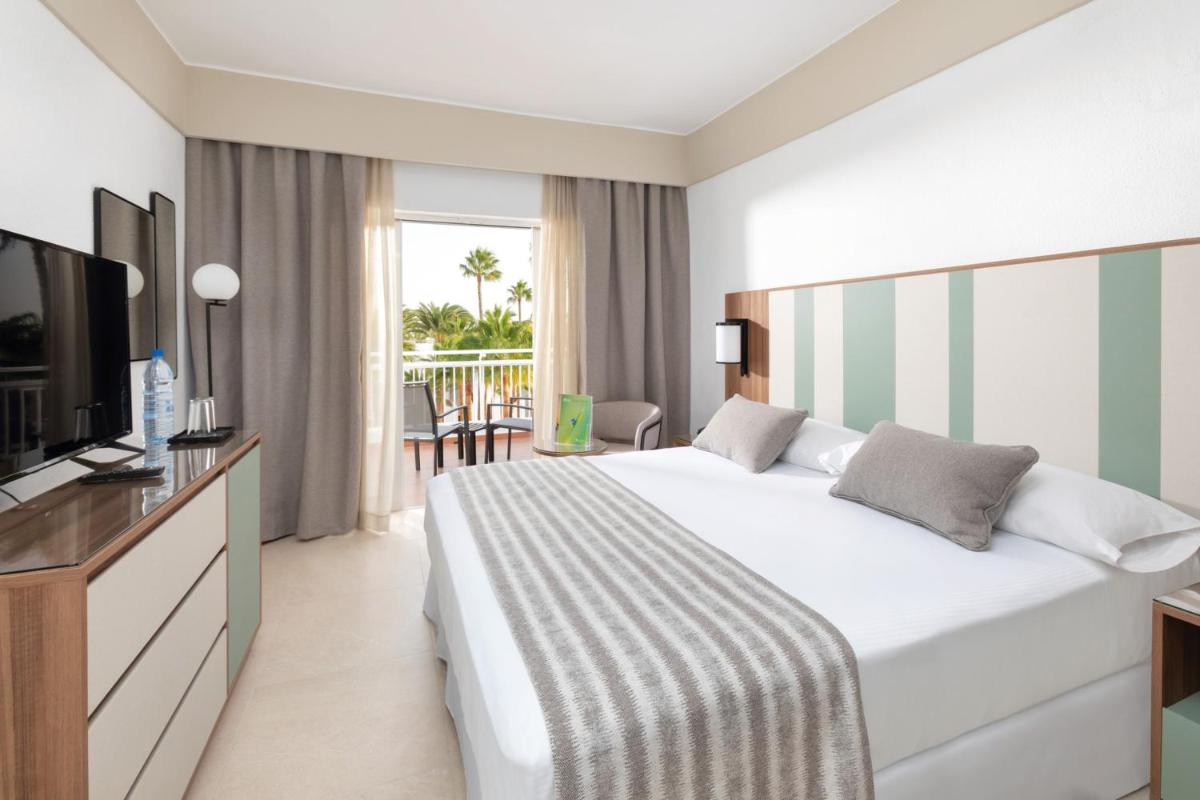 una habitación de hotel con una cama y un televisor en Hotel Riu Paraiso Lanzarote - All Inclusive, en Puerto del Carmen