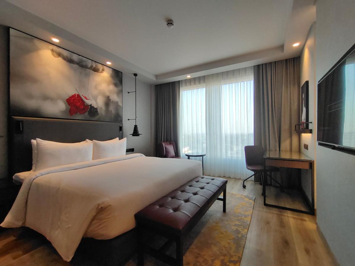 a hotel room with a large bed and a desk at Radisson RED Chandigarh Mohali in Chandīgarh