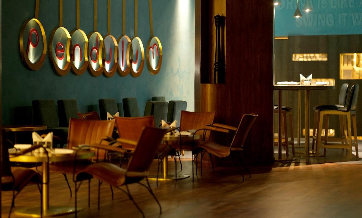 a dining room with chairs and a table and mirrors at The Centrum in Lucknow