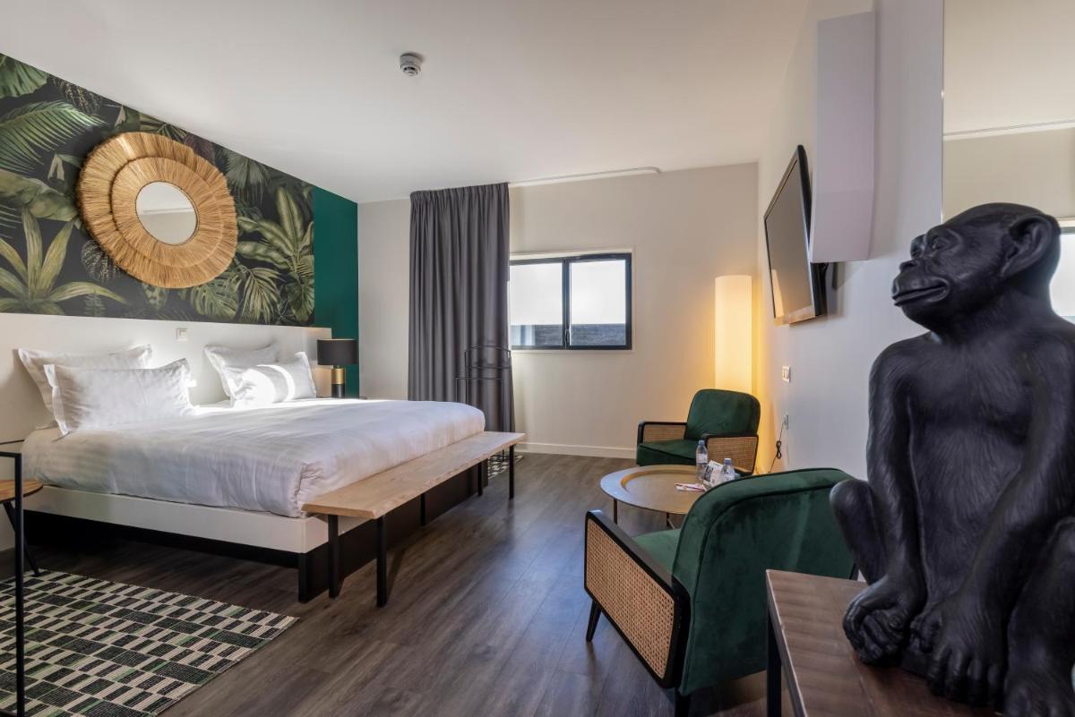 une chambre d'hôtel avec un lit, une table et des chaises dans l'établissement PADJA Hôtel & Spa Vannes, à Vannes