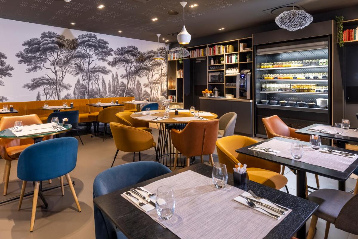 un restaurant avec des tables et des chaises et un bar dans l'établissement PADJA Hôtel & Spa Vannes, à Vannes