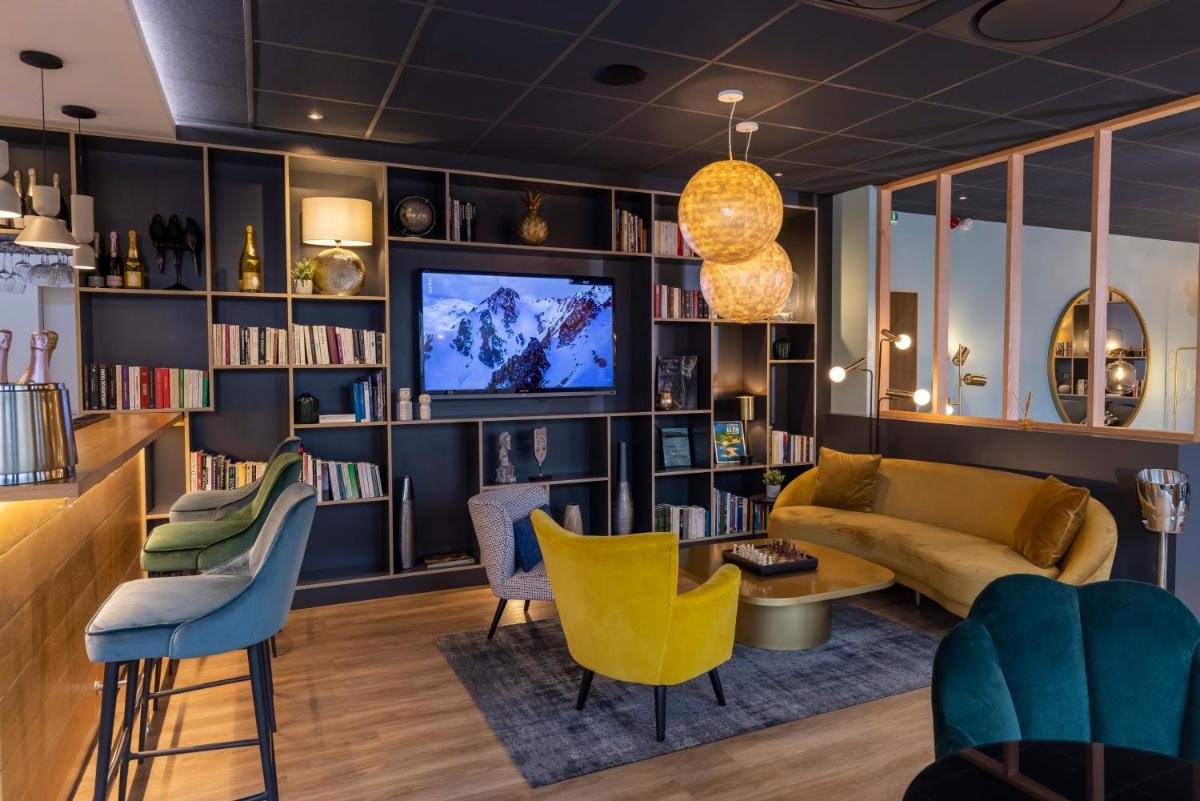 - un salon avec un canapé, une télévision et des chaises dans l'établissement PADJA Hôtel & Spa Vannes, à Vannes