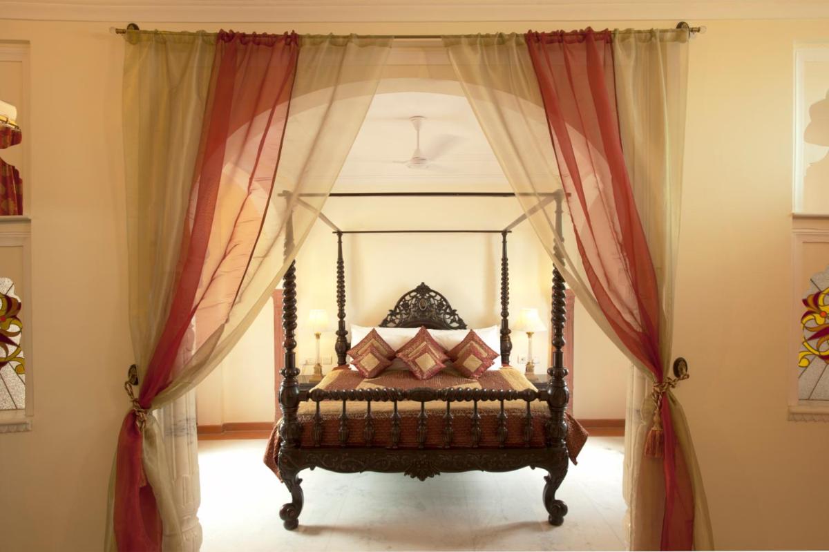 a bedroom with a bed with red curtains at Shahpura House in Jaipur