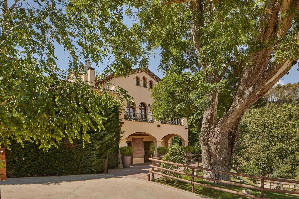 una casa grande con un árbol delante en Mas Salagros EcoResort & SPA, en Vallromanes