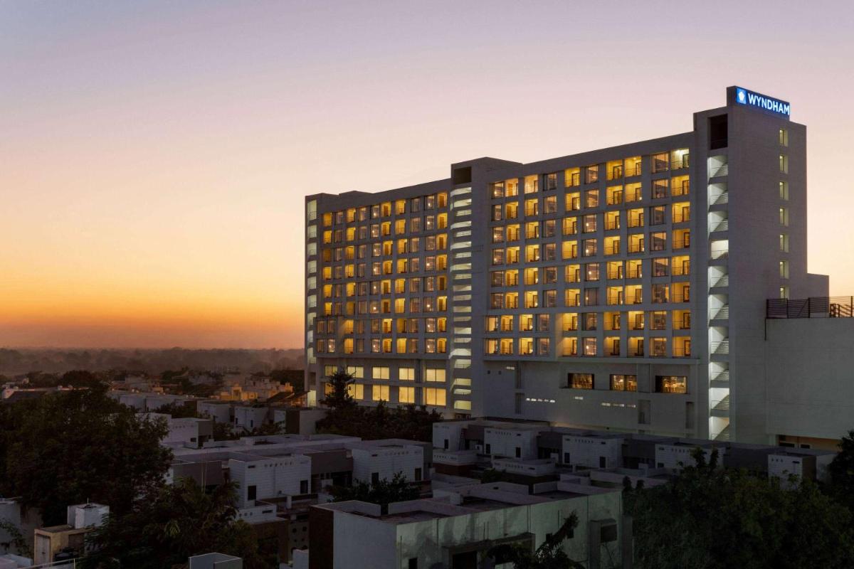 a hotel building with the sunset in the background at Wyndham Ahmedabad Shela in Ahmedabad
