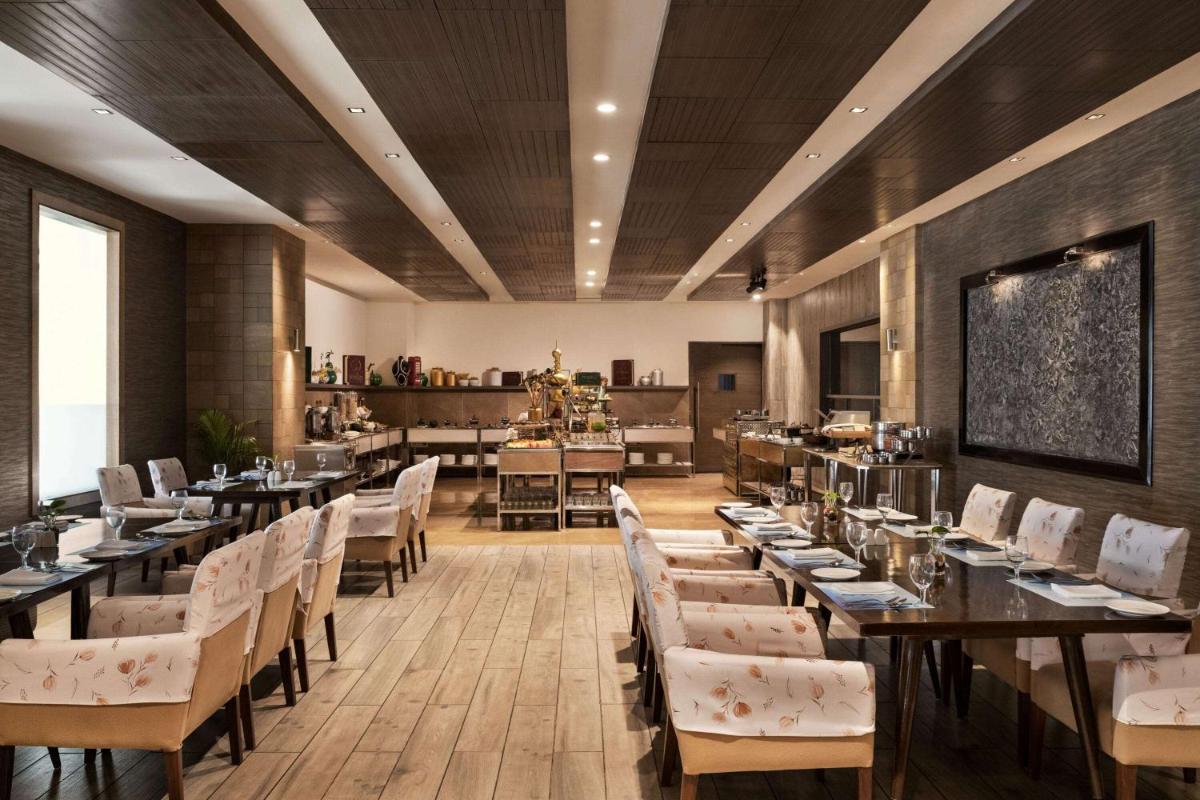a restaurant with tables and chairs in a room at Wyndham Ahmedabad Shela in Ahmedabad