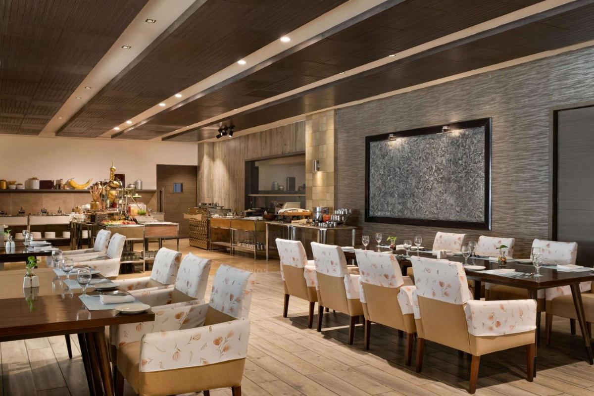 a restaurant with tables and chairs in a room at Wyndham Ahmedabad Shela in Ahmedabad