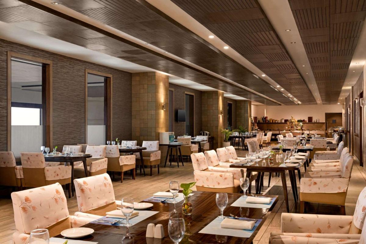 a restaurant with tables and chairs in a room at Wyndham Ahmedabad Shela in Ahmedabad