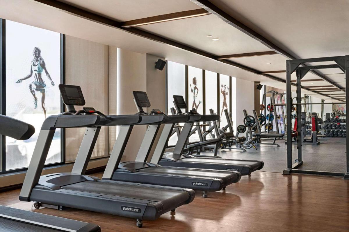a gym with rows of treadmills and machines at Wyndham Ahmedabad Shela in Ahmedabad