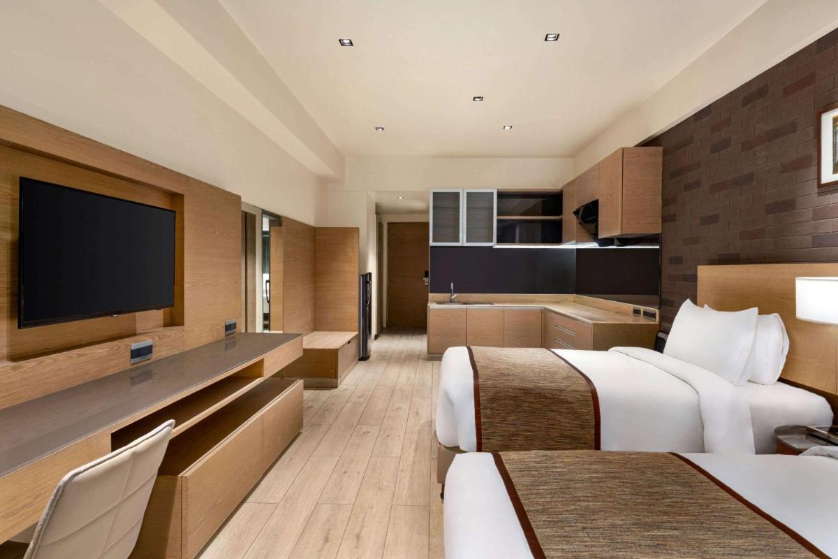 a hotel room with two beds and a flat screen tv at Wyndham Ahmedabad Shela in Ahmedabad