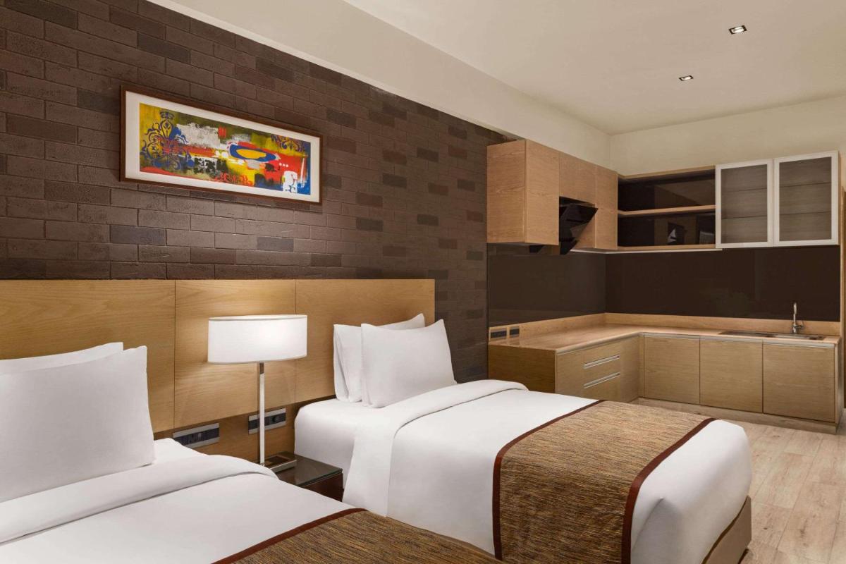 a hotel room with two beds and a kitchen at Wyndham Ahmedabad Shela in Ahmedabad