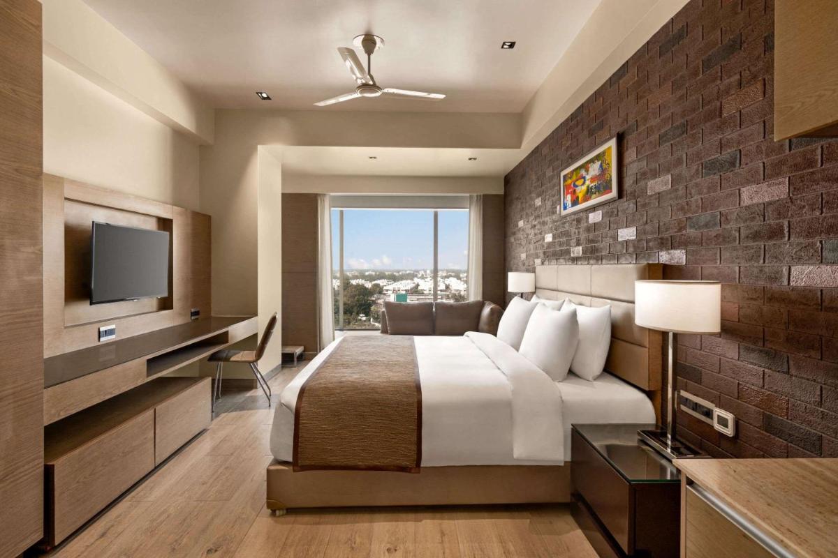 a hotel room with a bed and a television at Wyndham Ahmedabad Shela in Ahmedabad