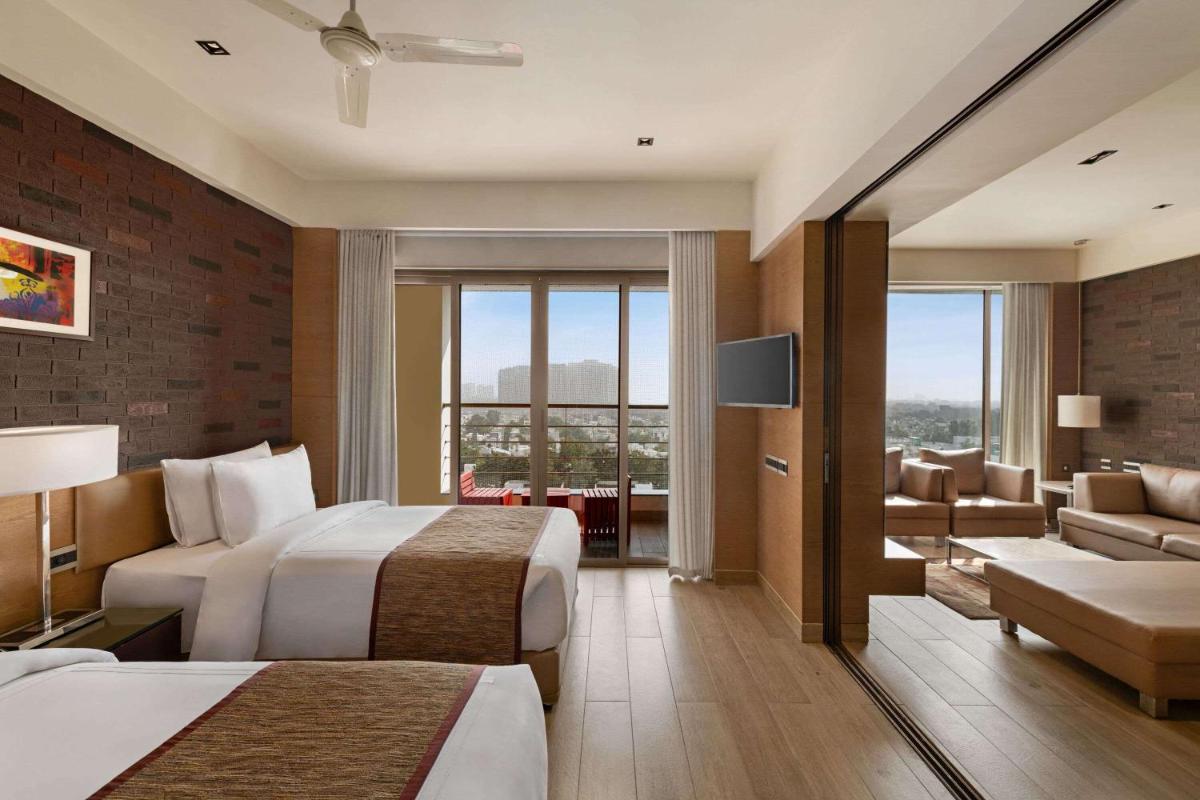 a hotel room with two beds and a living room at Wyndham Ahmedabad Shela in Ahmedabad