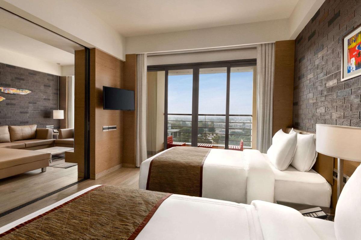 a hotel room with two beds and a couch at Wyndham Ahmedabad Shela in Ahmedabad