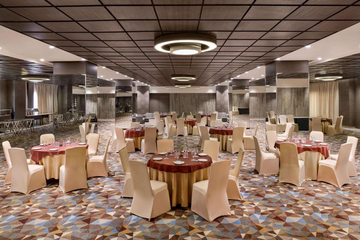 a banquet hall with tables and white chairs at Wyndham Ahmedabad Shela in Ahmedabad