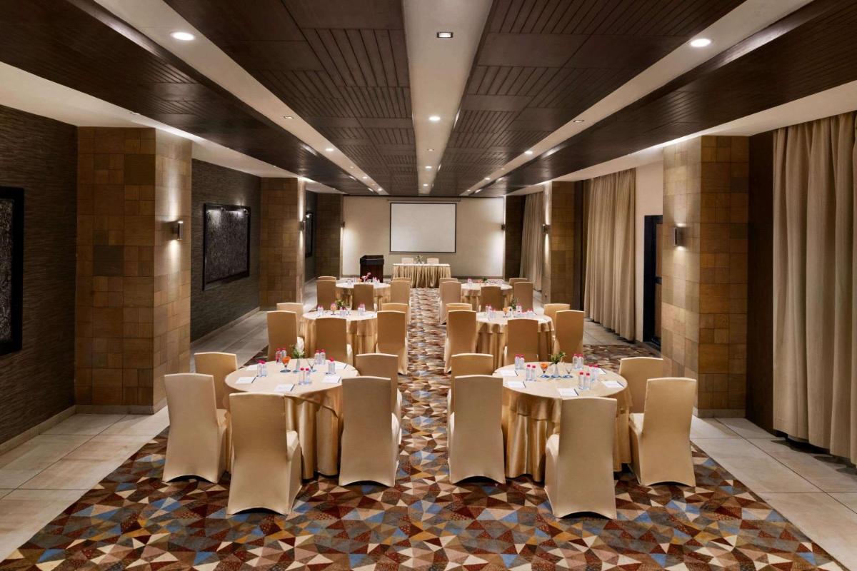a banquet hall with tables and chairs and a screen at Wyndham Ahmedabad Shela in Ahmedabad