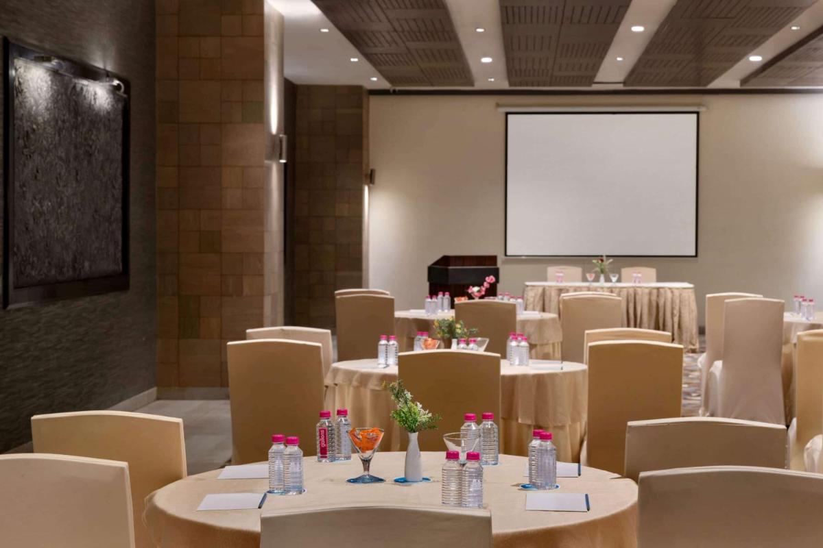 a conference room with tables and chairs and a white screen at Wyndham Ahmedabad Shela in Ahmedabad