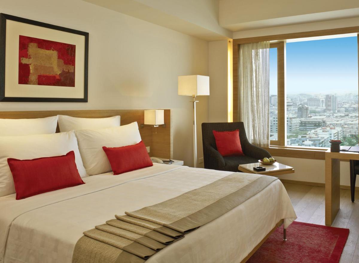 a bedroom with a large bed with a chair and a window at Trident Nariman Point in Mumbai a bedroom with a large bed with a chair and a window at Trident Nariman Point in Mumbai