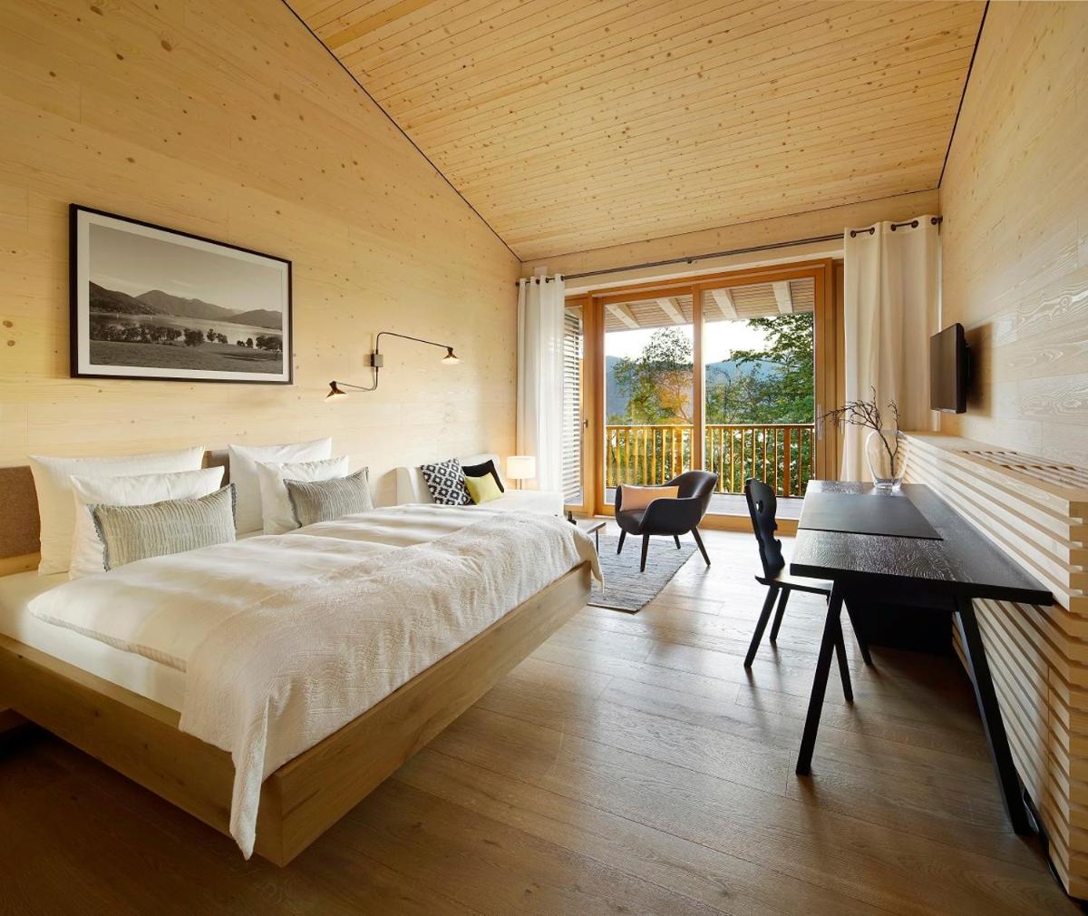 ein Schlafzimmer mit einem Bett, einem Schreibtisch und einem Fenster in der Unterkunft Das Tegernsee in Tegernsee ein Schlafzimmer mit einem Bett, einem Schreibtisch und einem Fenster in der Unterkunft Das Tegernsee in Tegernsee