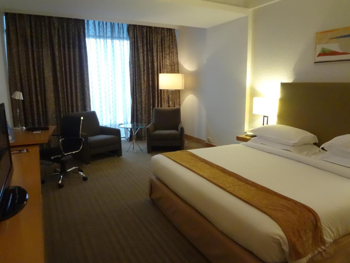 a hotel room with a bed and a desk and chairs at Radisson Blu Hotel Pune Kharadi in Pune