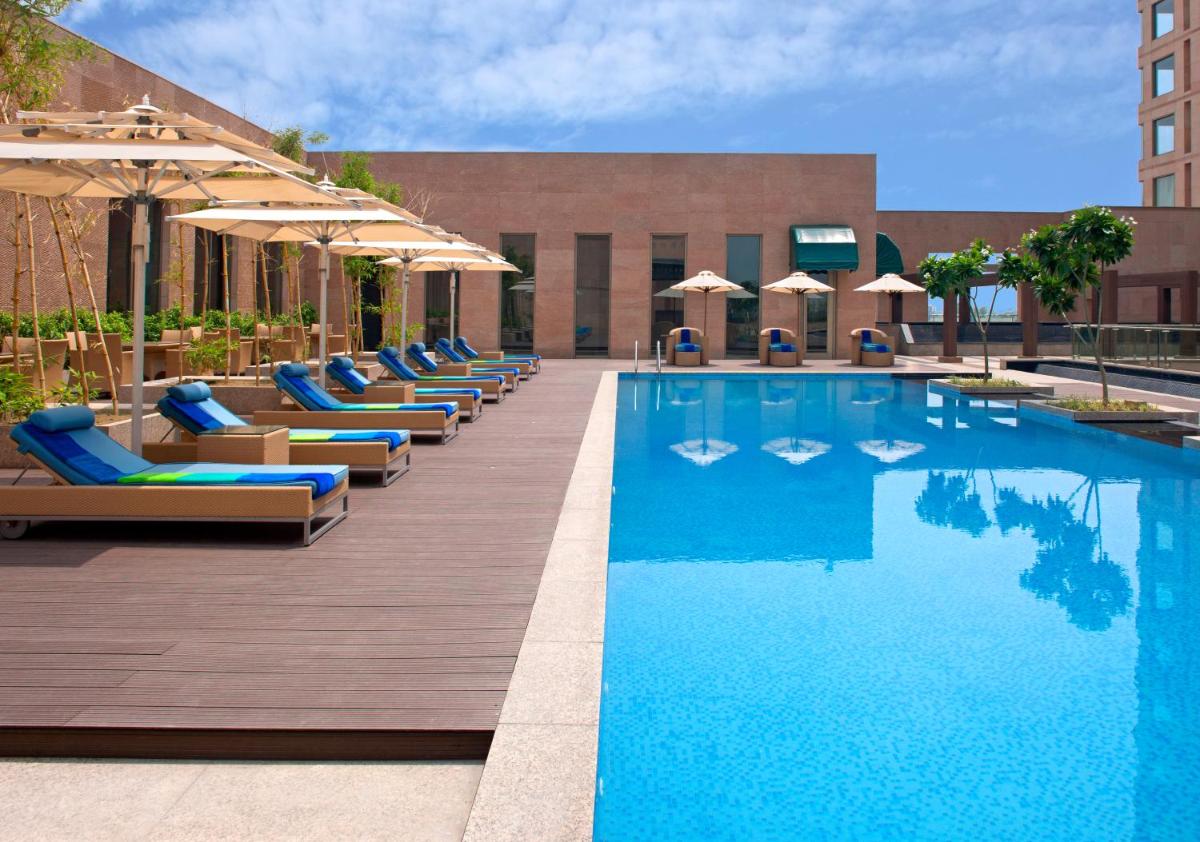 a pool with lounge chairs and umbrellas next to a building at Radisson Blu Hotel Amritsar in Amritsar