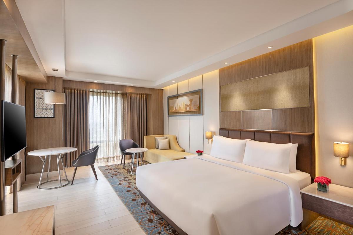 a hotel room with a large bed and a living room at Radisson Blu Hotel Amritsar in Amritsar +92 photos
