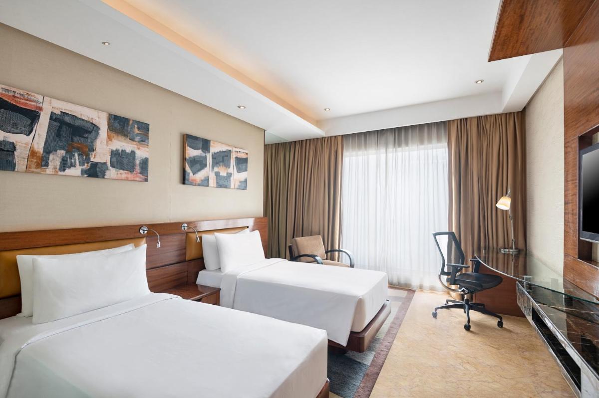a hotel room with two beds and a tv at Radisson Blu Kaushambi Delhi NCR in Ghaziabad