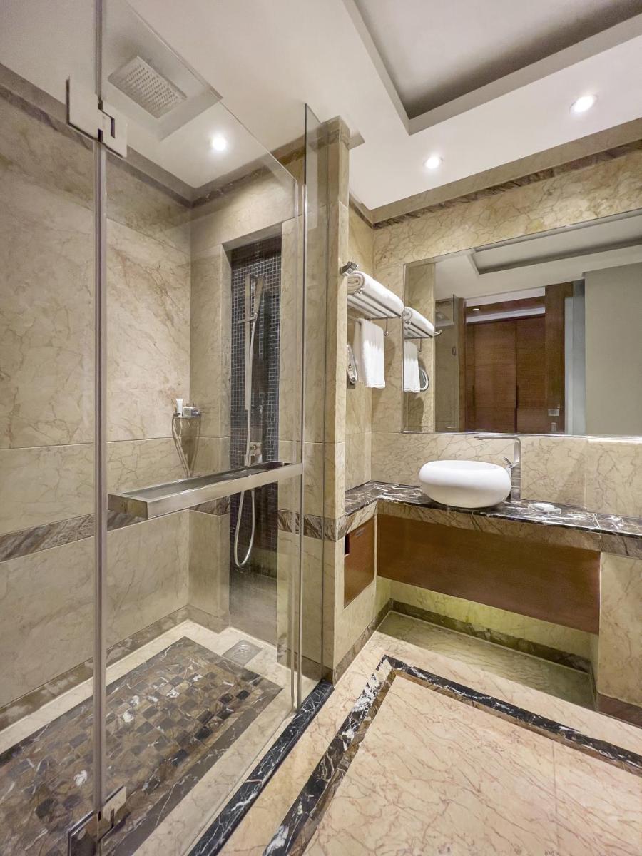 a bathroom with a glass shower and a sink at Radisson Blu Kaushambi Delhi NCR in Ghaziabad