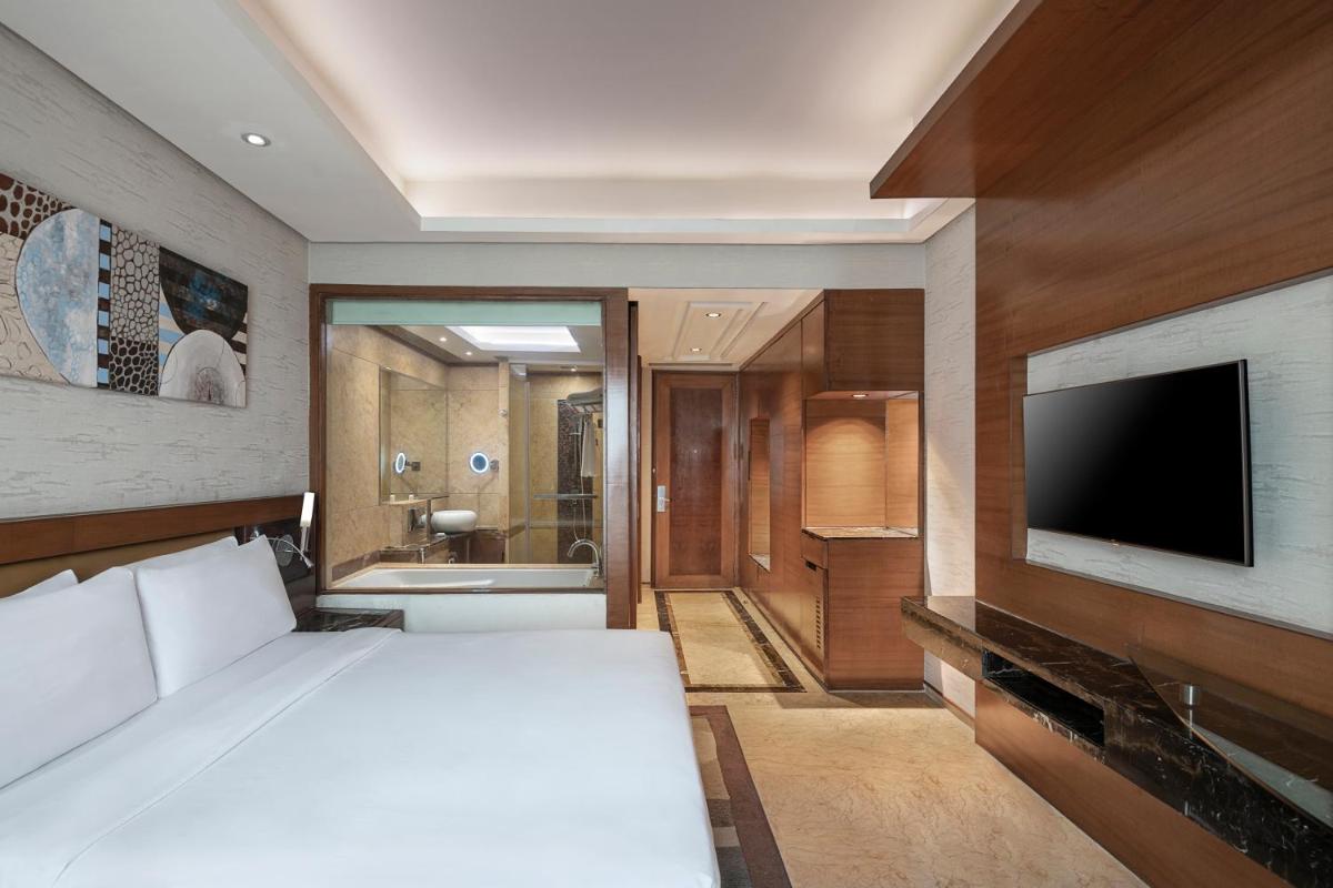 a bedroom with a white bed and a television at Radisson Blu Kaushambi Delhi NCR in Ghaziabad