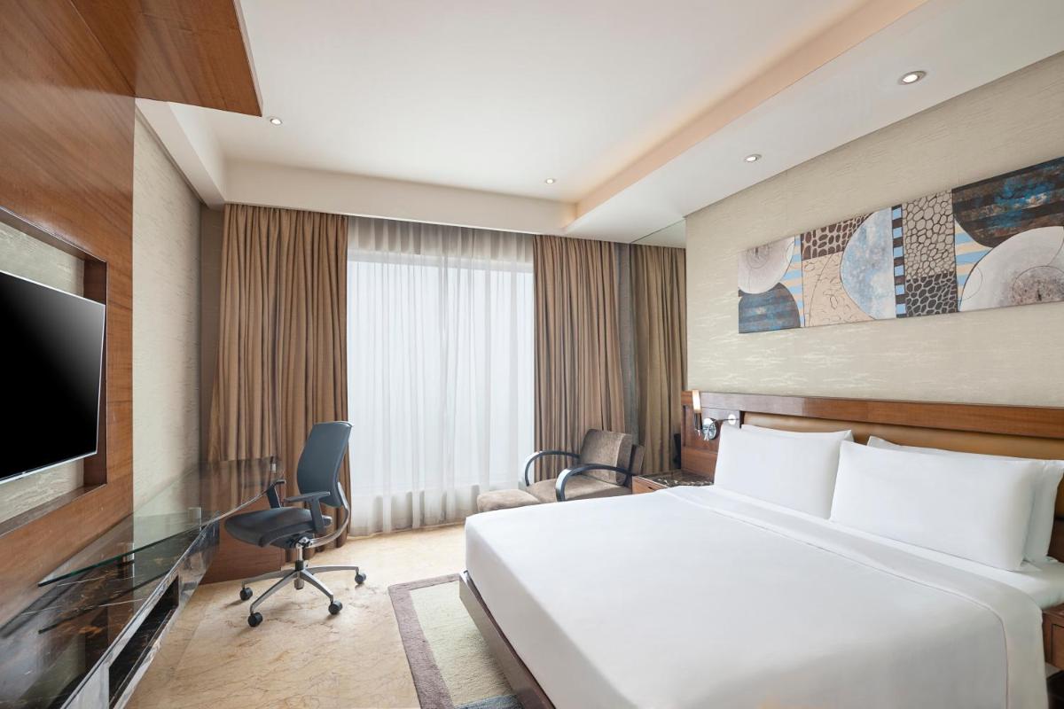 a hotel room with a bed and a flat screen tv at Radisson Blu Kaushambi Delhi NCR in Ghaziabad
