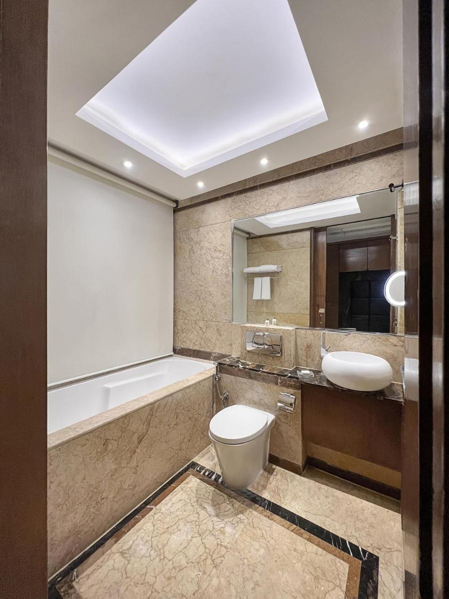 a bathroom with a toilet and a sink and a mirror at Radisson Blu Kaushambi Delhi NCR in Ghaziabad