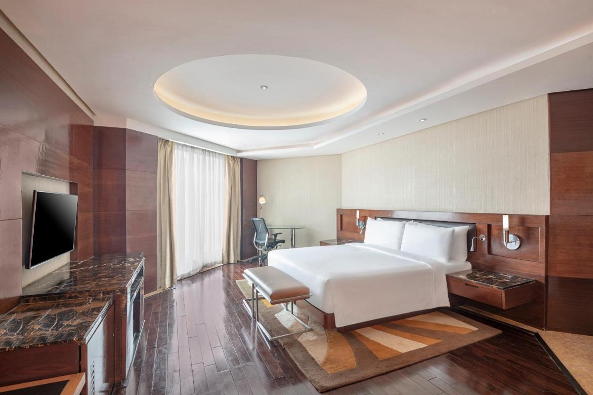 a hotel room with a white bed and a television at Radisson Blu Kaushambi Delhi NCR in Ghaziabad