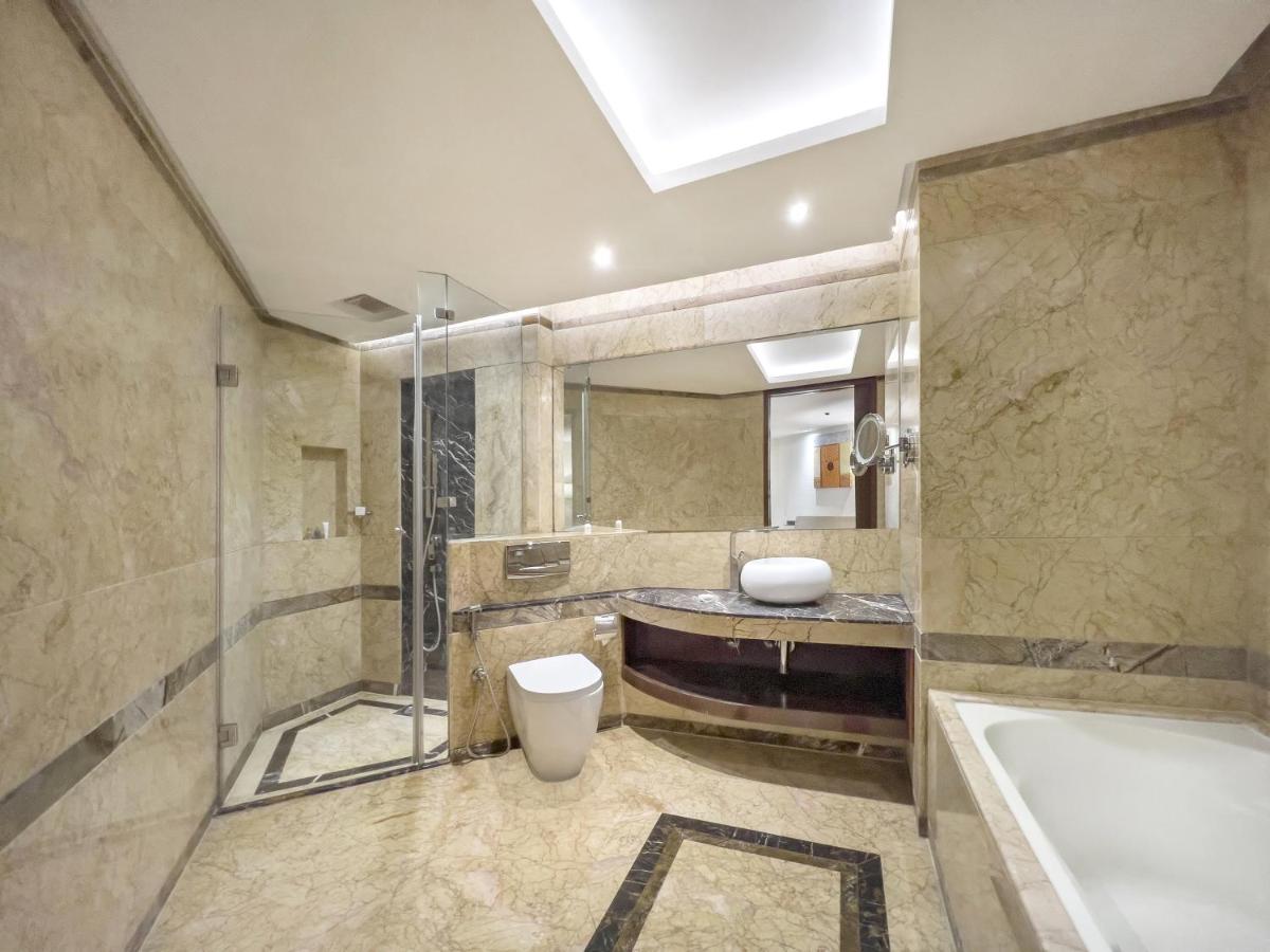 a bathroom with a tub and a toilet and a sink at Radisson Blu Kaushambi Delhi NCR in Ghaziabad
