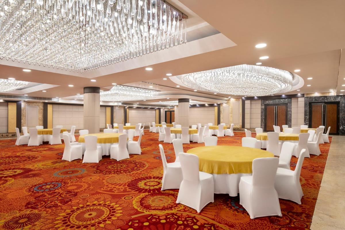 a banquet hall with white chairs and tables and chandeliers at Radisson Blu Kaushambi Delhi NCR in Ghaziabad