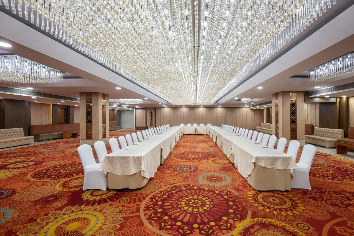 a banquet hall with white chairs and a large ceiling at Radisson Blu Kaushambi Delhi NCR in Ghaziabad
