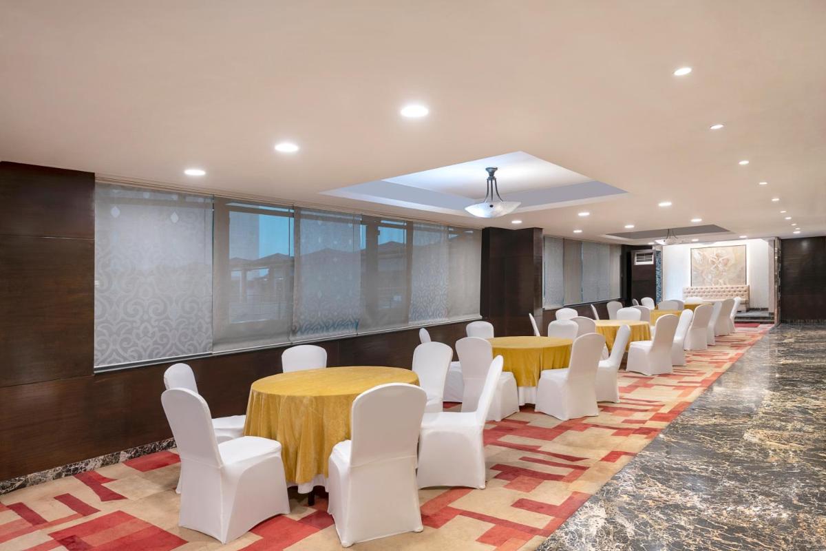 a conference room with tables and white chairs at Radisson Blu Kaushambi Delhi NCR in Ghaziabad