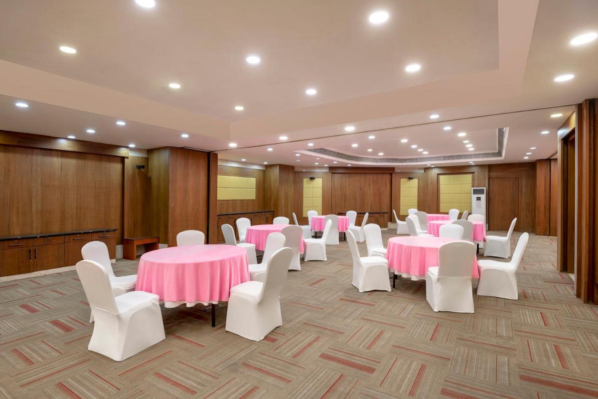 a banquet hall with pink tables and white chairs at Radisson Blu Kaushambi Delhi NCR in Ghaziabad