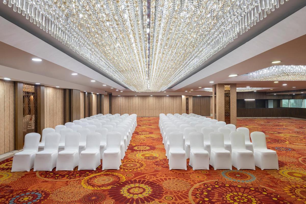 a row of white chairs in a room with a ceiling at Radisson Blu Kaushambi Delhi NCR in Ghaziabad