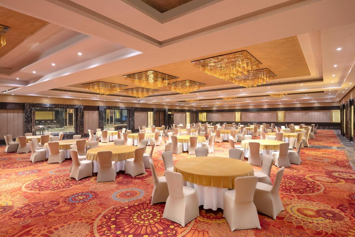 a large banquet hall with tables and white chairs at Radisson Blu Kaushambi Delhi NCR in Ghaziabad