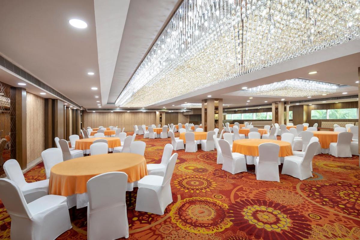 a large banquet hall with tables and white chairs at Radisson Blu Kaushambi Delhi NCR in Ghaziabad