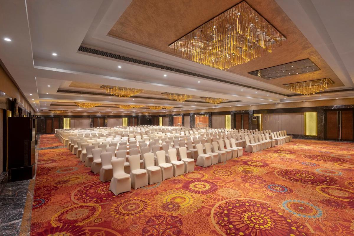 a large banquet hall with white chairs and a chandelier at Radisson Blu Kaushambi Delhi NCR in Ghaziabad