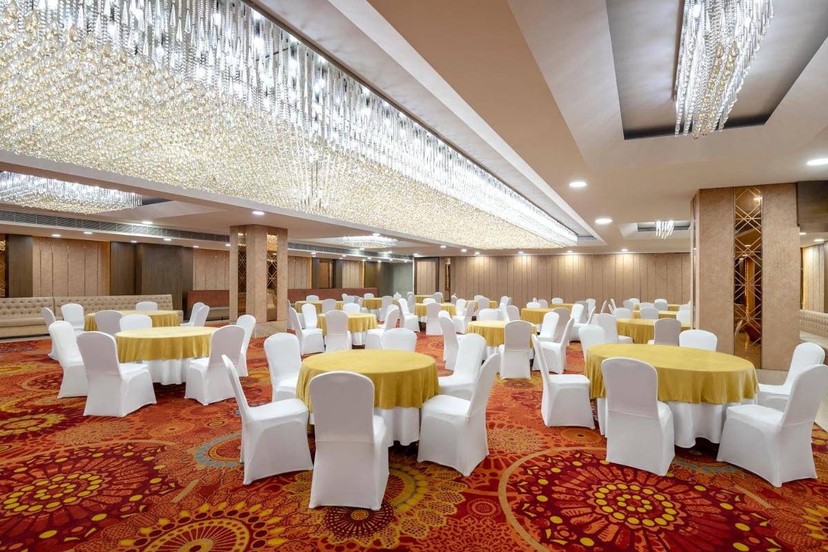 a room with tables and chairs and chandeliers at Radisson Blu Kaushambi Delhi NCR in Ghaziabad