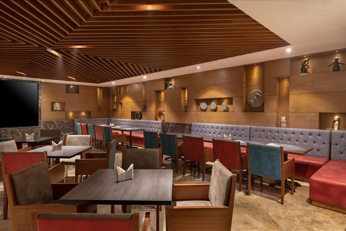 a restaurant with tables and chairs and a bar at Radisson Blu Kaushambi Delhi NCR in Ghaziabad