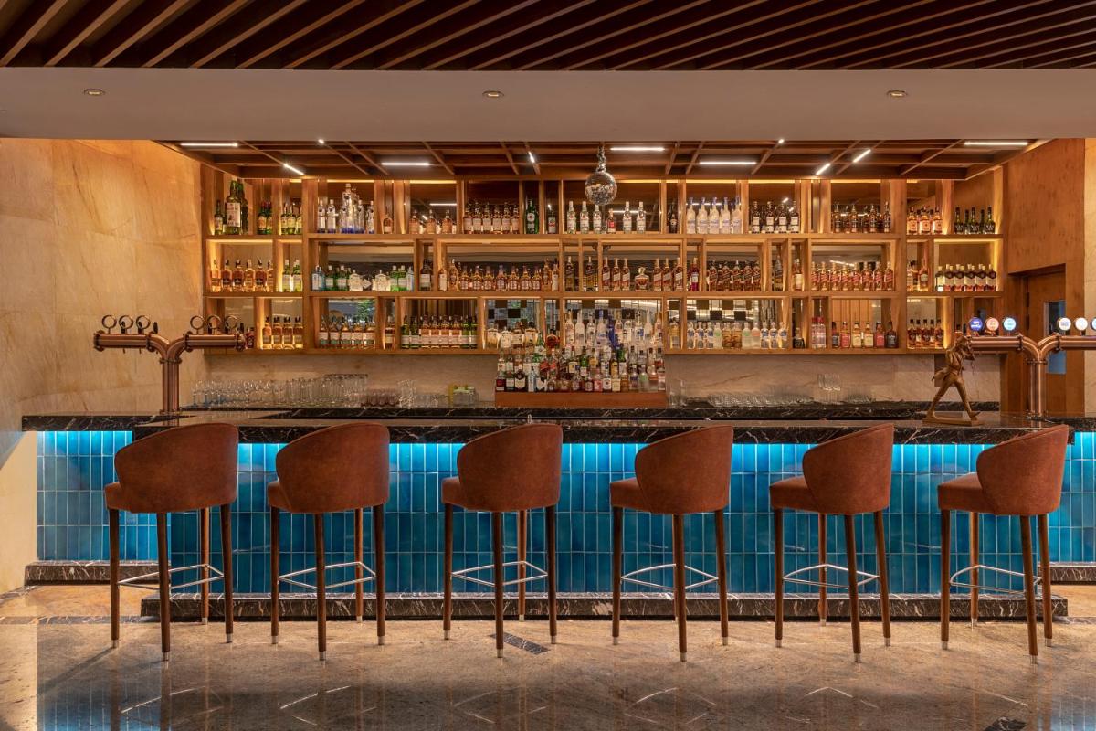 a bar with brown stools in front of a blue counter at Radisson Blu Kaushambi Delhi NCR in Ghaziabad