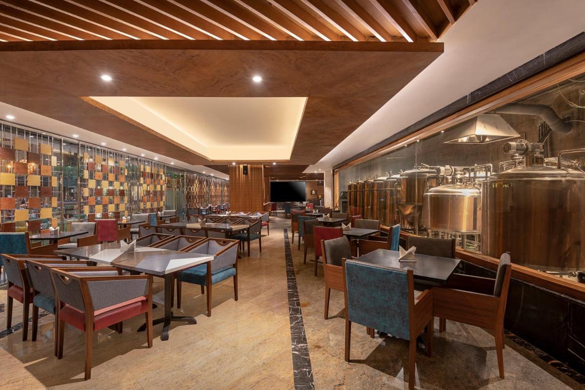 a restaurant with tables and chairs and a kitchen at Radisson Blu Kaushambi Delhi NCR in Ghaziabad