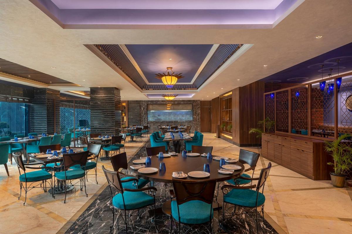 a restaurant with tables and chairs in a room at Radisson Blu Kaushambi Delhi NCR in Ghaziabad