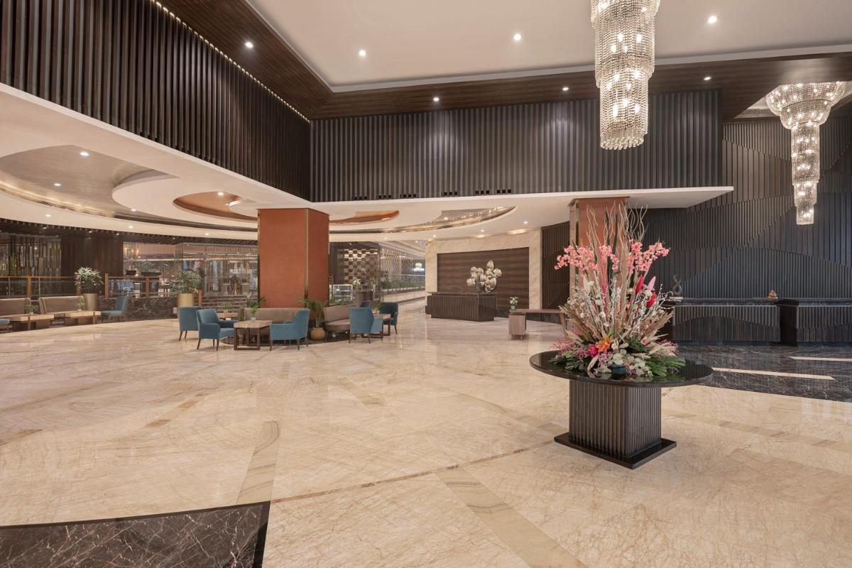 a lobby of a hotel with chairs and a table with flowers at Radisson Blu Kaushambi Delhi NCR in Ghaziabad